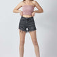 Woman wearing Risen Jeans raw hem denim shorts with pockets, paired with a pink strapless top and black ankle boots.