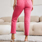 Woman wearing RFM Jeans Crop Dylan Full Size Tummy Control High Waist Raw Hem Pink Jeans with a white top and high heels.