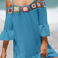 Woman wearing blue crochet cold shoulder three-quarter sleeve cover up with floral design at the beach.