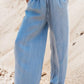 Woman wearing Bella Road Drawstring Wide Leg Jeans in medium blue, showcasing comfort and relaxed style on the beach.