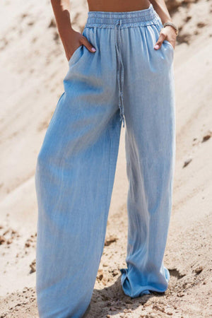 Woman wearing Bella Road Drawstring Wide Leg Jeans in medium blue, showcasing comfort and relaxed style on the beach.