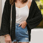 Woman wearing openwork open front dropped shoulder black cardigan over white tank top with denim shorts