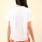 Woman wearing a notched short sleeve washed T-shirt and an orange skirt, showcasing the back view of the casual, stylish top.