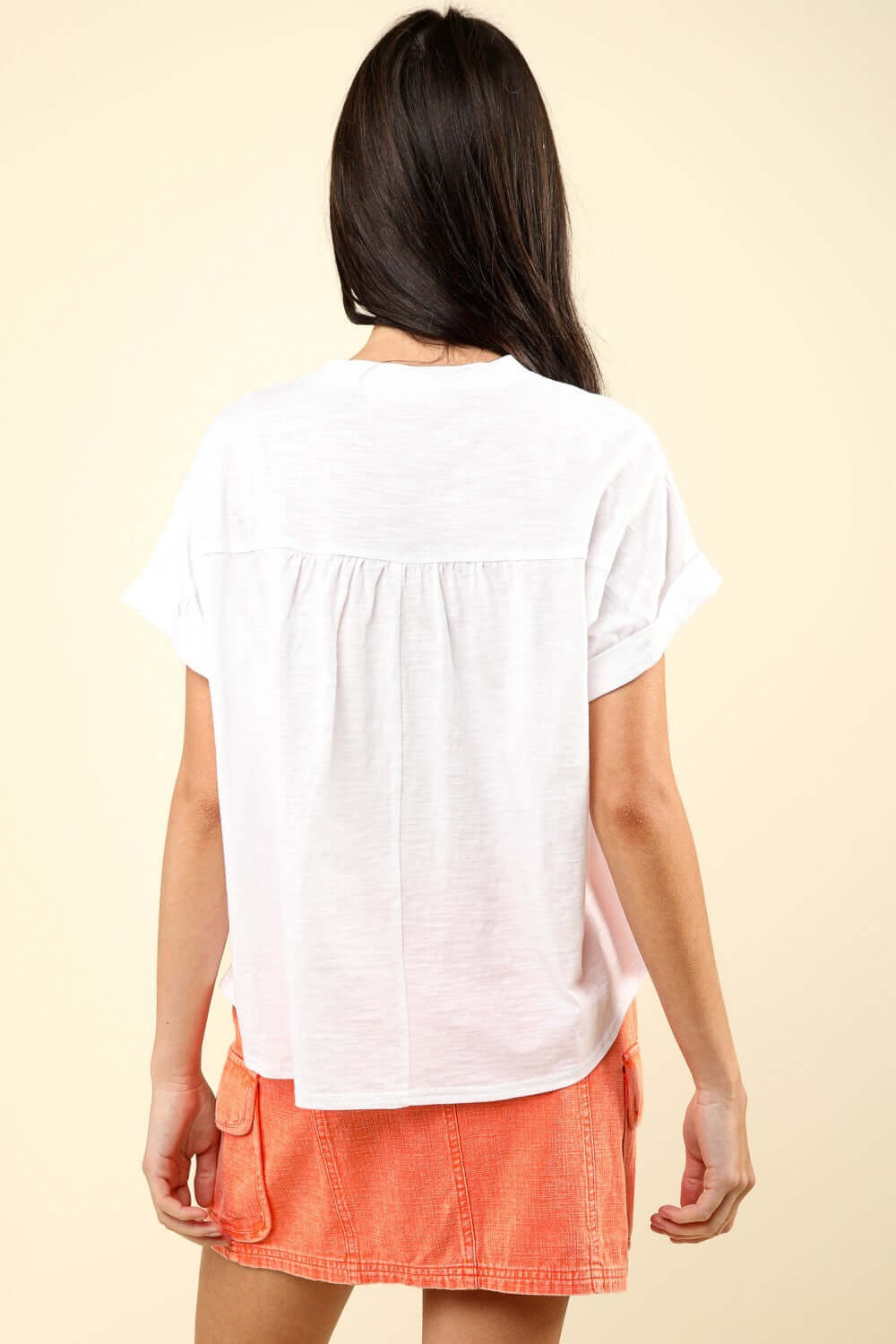 Woman wearing a notched short sleeve washed T-shirt and an orange skirt, showcasing the back view of the casual, stylish top.