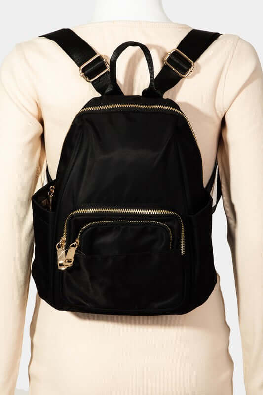 Stylish black nylon multi pocket backpack with gold zippers, perfect for organization on any adventure.