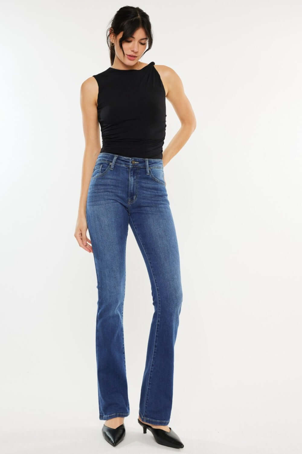 Woman models Kancan high-rise slim bootcut jeans in medium stone wash, showcasing a versatile denim style ideal for various occasions.