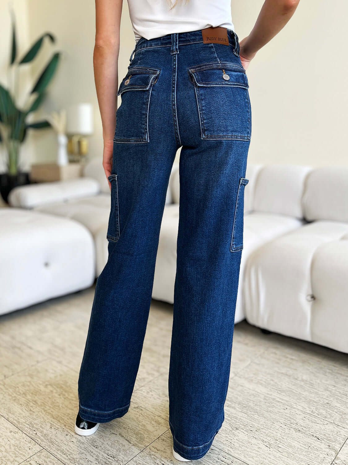 Woman wearing high waist straight cargo jeans from Judy Blue Jeans with back pockets in a modern living room setting.