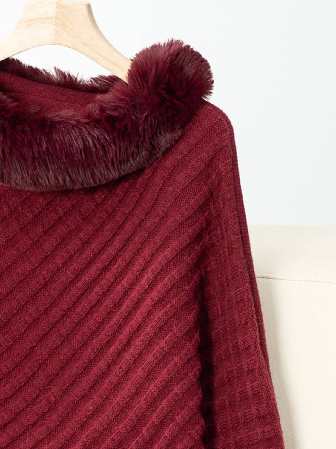 Cozy Bella Road fuzzy trim poncho in burgundy with textured fabric and three-quarter sleeves hanging on a wooden hanger.