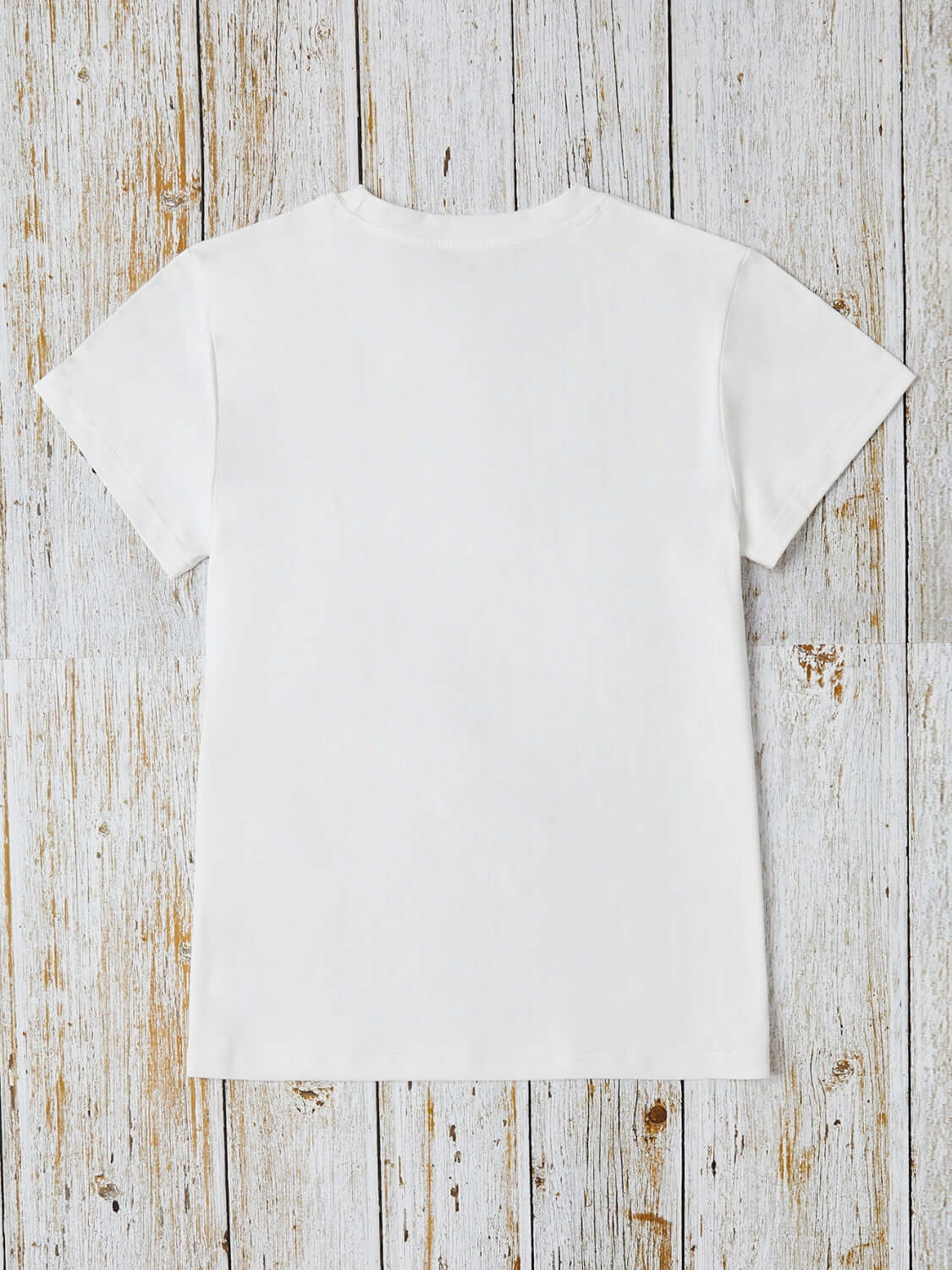 Back view of white graphic round neck short sleeve t-shirt made of 100% polyester, lying on wooden surface.