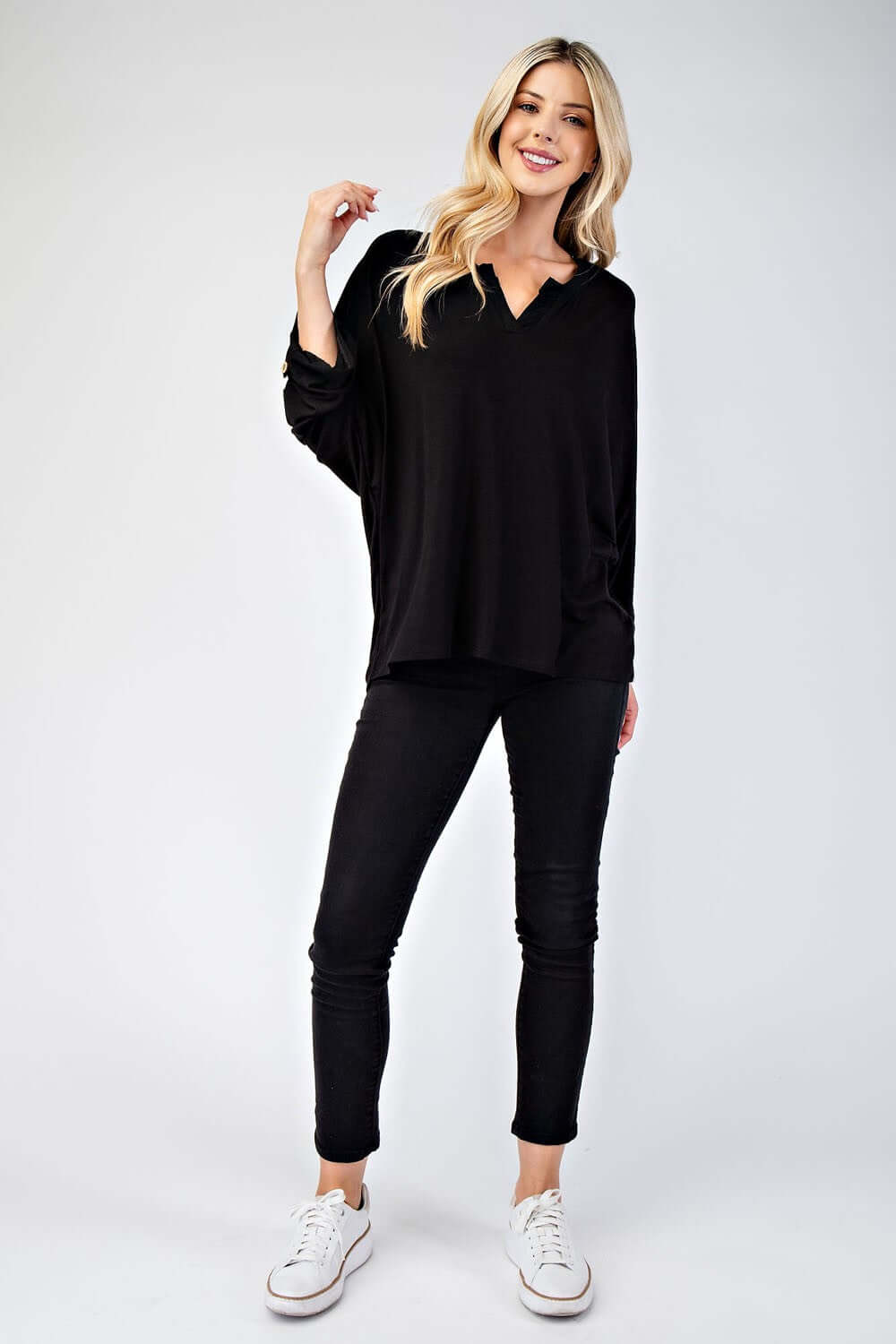 Stylish model wearing a black Celeste notched three-quarter sleeve blouse with jeans and sneakers, perfect for casual looks.