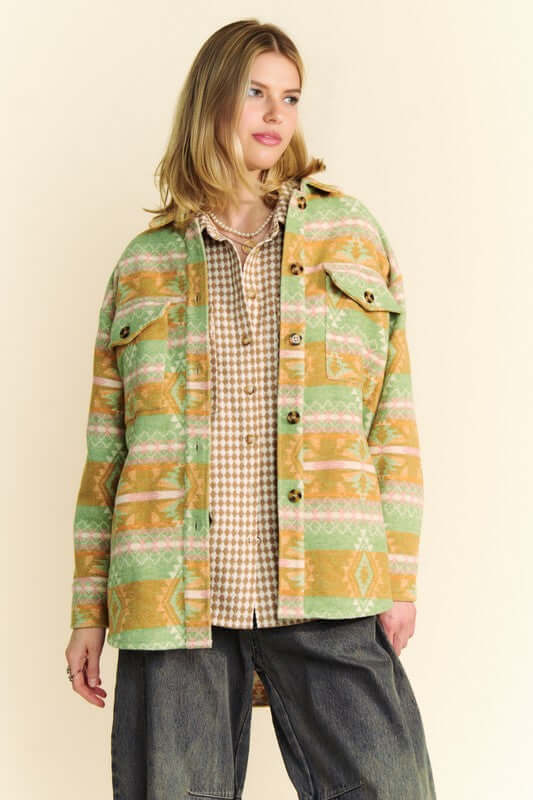 Model wearing a stylish High-Low Geometric Long Sleeve Shacket with pockets, showcasing a vibrant green and orange pattern.