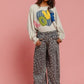 Model wearing BiBi LOVE Heart Patch Slit French Terry Sweatshirt with floral pants against a pink background.