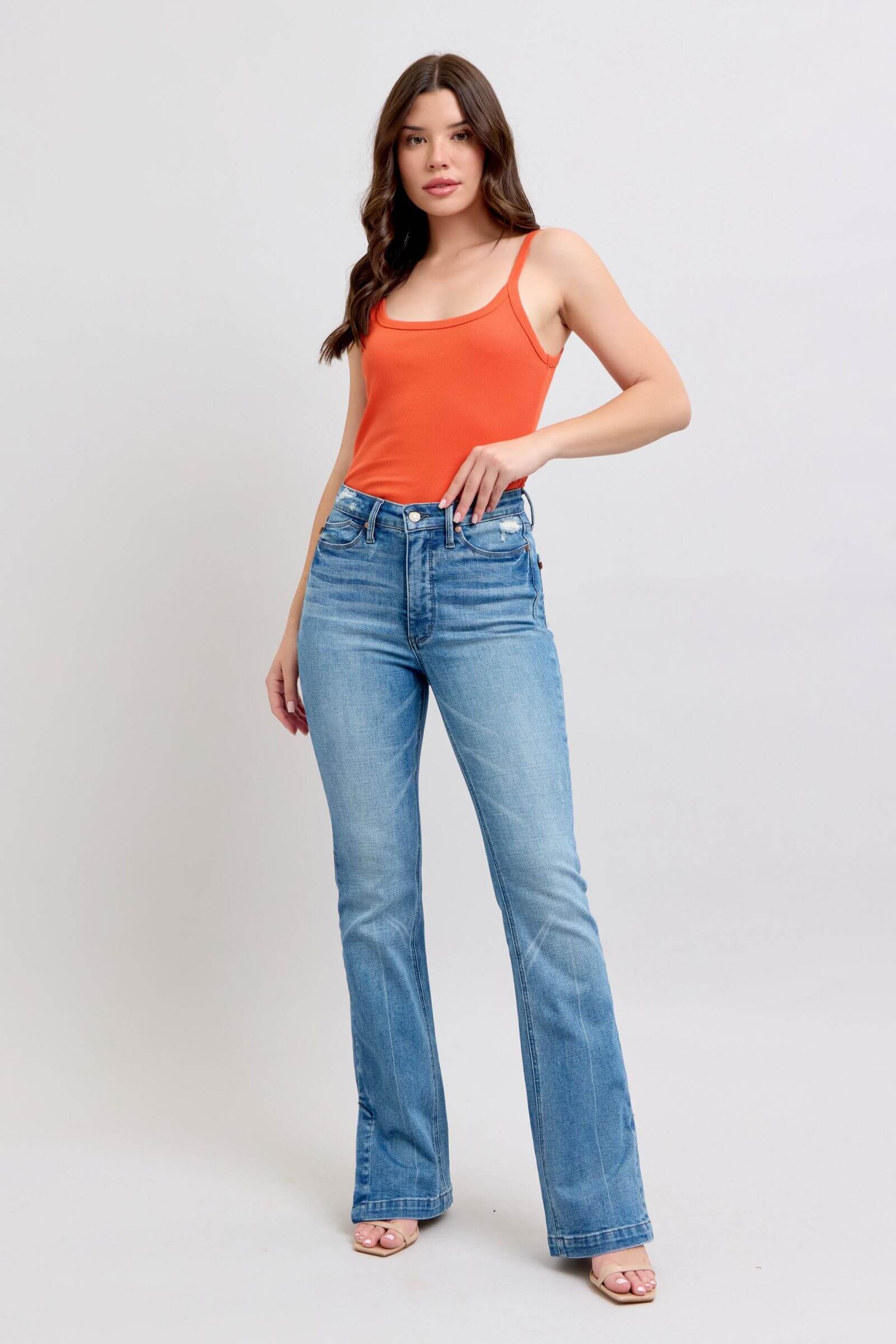 Model wearing Judy Blue high waist tummy control vintage wash bootcut jeans with orange tank top and stylish side slit.