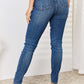 Woman wearing mid waist distressed slim jeans Judy Blue, back view showcasing flattering fit and distressed detailing, with heels