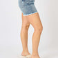 Side view of model wearing Judy Blue Jeans Button Fly Raw Hem Denim Shorts showcasing trendy and stylish summer casual fashion.