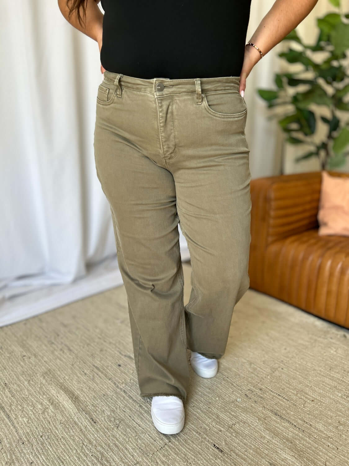 Woman wearing RFM Full Size High Rise Garment Dye Wide Leg Jeans with a stylish high-waist fit in a unique, rich color, paired with white sneakers.