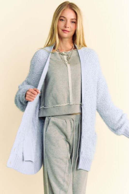 Woman wearing a light blue ribbed hem cardigan over a gray outfit, showcasing a stylish and comfortable layered look.