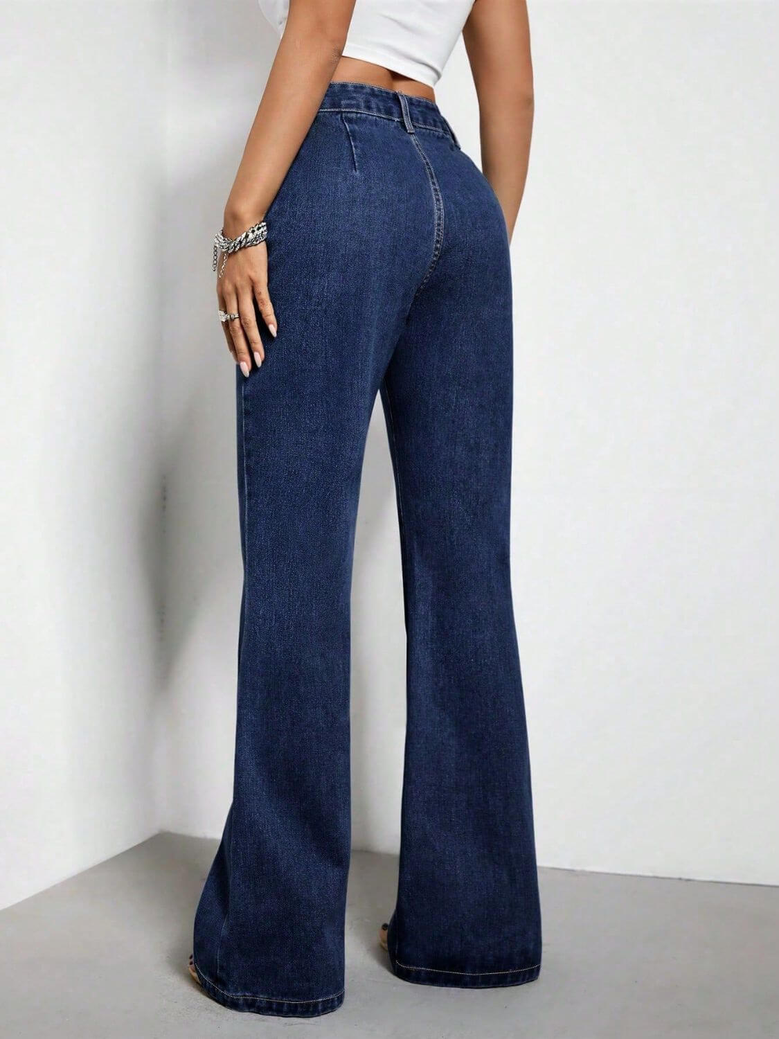 Woman wearing high waist bootcut jeans with pockets in dark wash, back view.