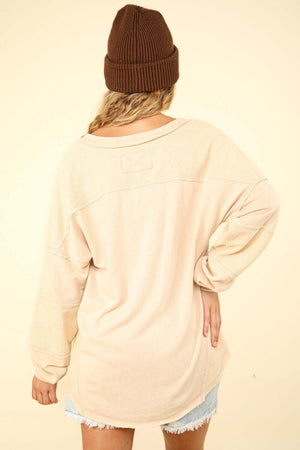 Back view of VERY J Washed V-Neck Exposed Seam Knit Top with drop shoulders, long sleeves, raw edge detail, and exposed seams in beige color.