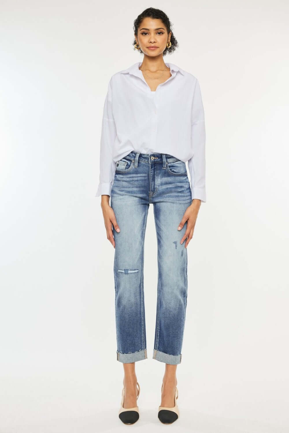 Woman wearing high rise cuffed straight jeans and white shirt with black heels