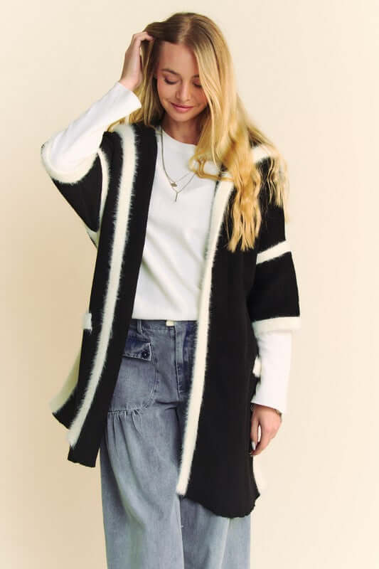 Woman modeling a Davi & Dani fuzzy trim open front cardigan with black and white stripes over a casual outfit.