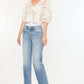 Woman wearing Kancan Mid Rise Frayed Hem Straight Jeans in medium wash with a floral blouse, showcasing casual chic style.