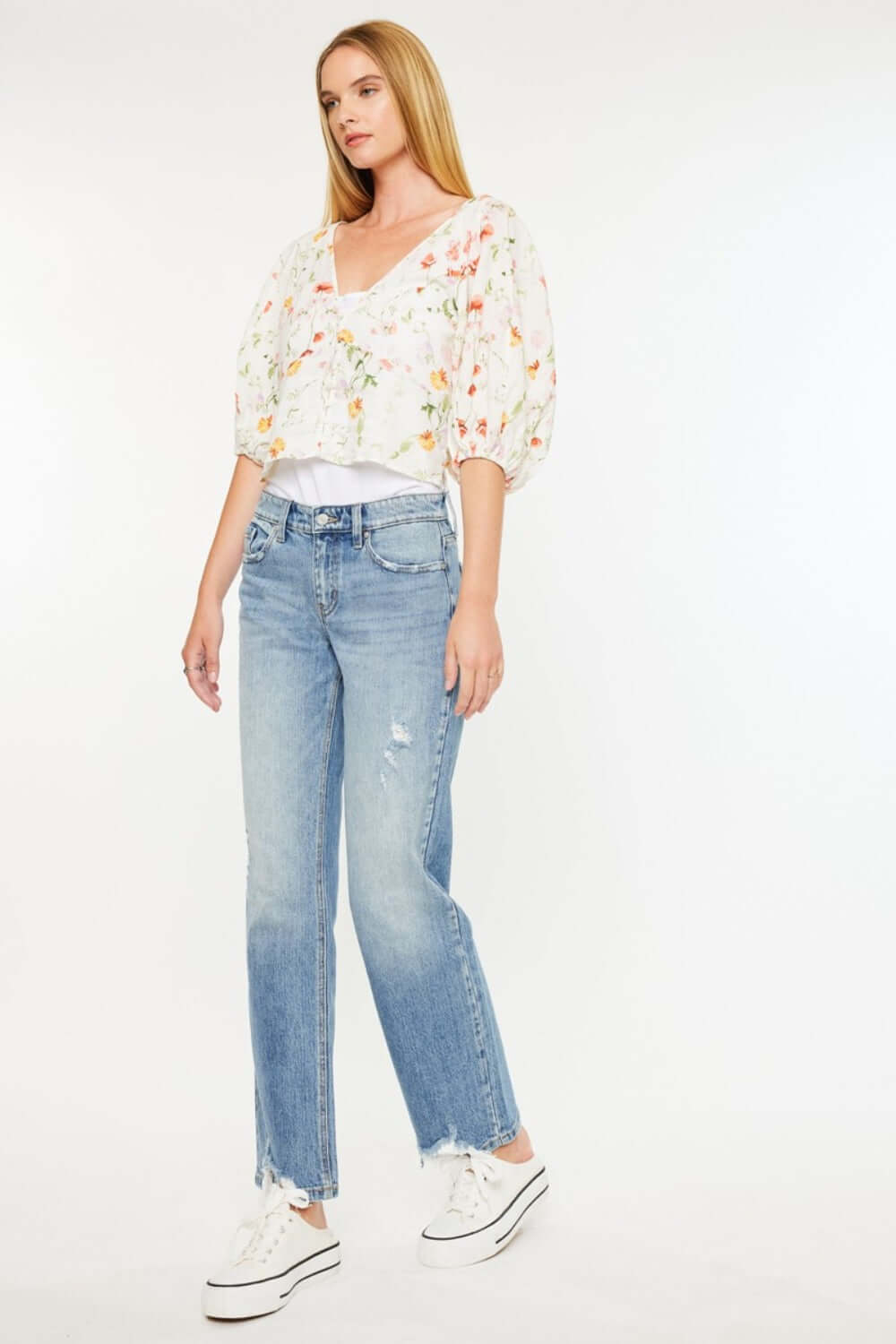 Woman wearing Kancan Mid Rise Frayed Hem Straight Jeans in medium wash with a floral blouse, showcasing casual chic style.