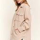 Woman wearing cozy beige teddy sherpa button-down shacket with curved hem, showing stylish layering with relaxed fit and pockets.