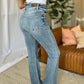 Woman wearing Judy Blue medium rise bootcut jeans in a living room, showcasing the comfortable fit and classic style.