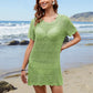 Model wearing Bella Road Swim Openwork Round Neck Short Sleeve Cover-Up in green at the beach with ocean background.