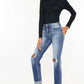 Woman wearing high waist distressed hem detail cropped straight jeans with a black top and sneakers.