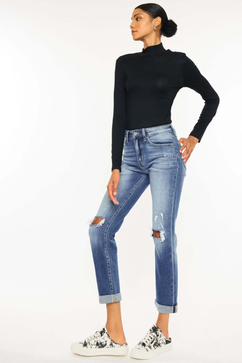 Woman wearing high waist distressed hem detail cropped straight jeans with a black top and sneakers.