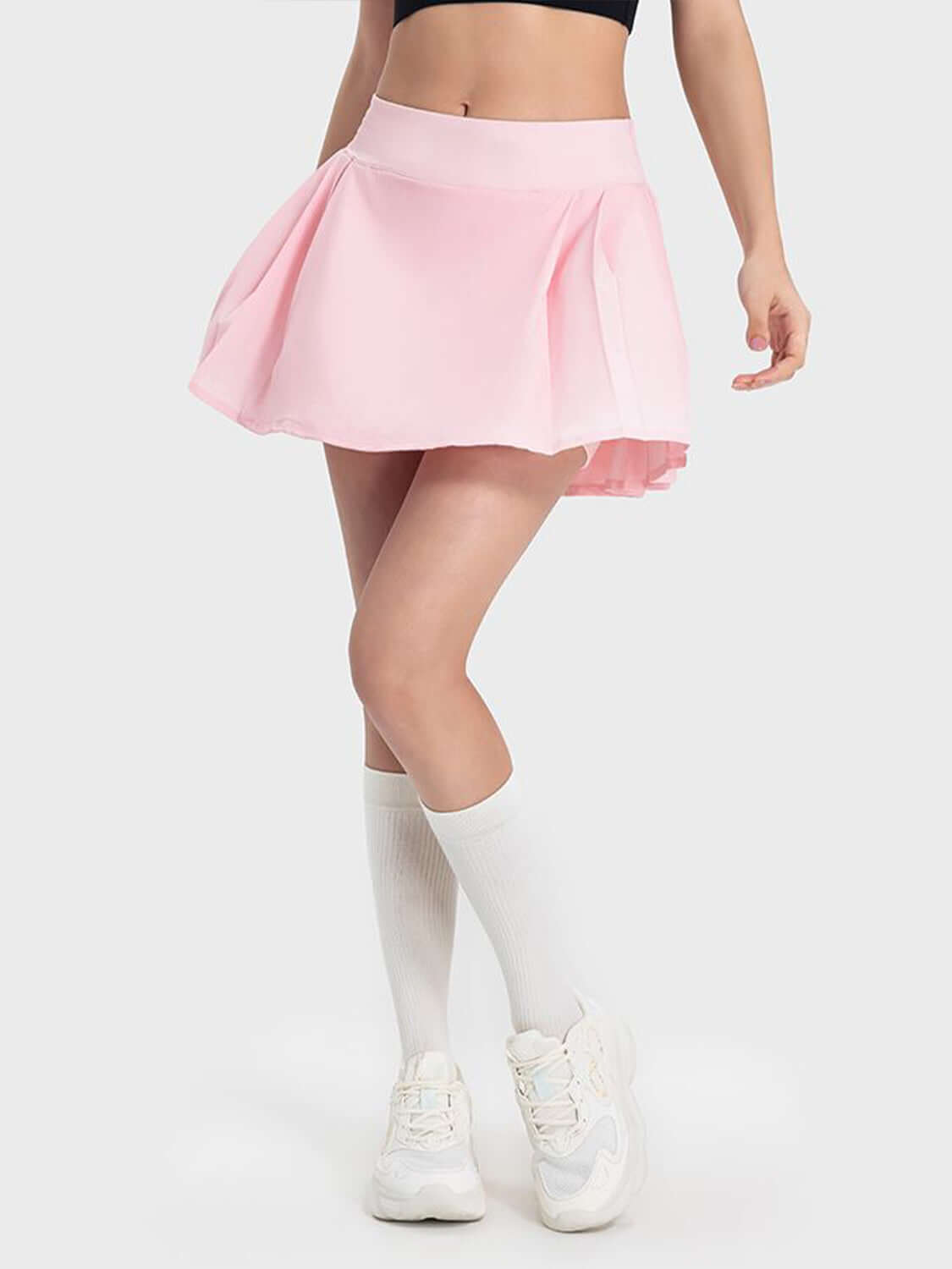 Fun and flirty pink pleated active skirt with mid-rise waist, perfect for stylish workouts and everyday wear.