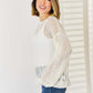 Woman wearing Openwork Ribbed Trim Long Sleeve Knit Top in white paired with blue jeans.