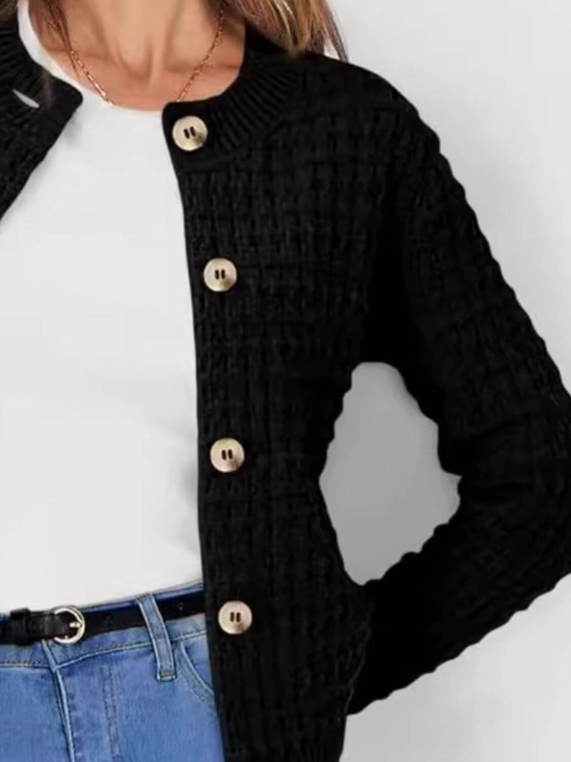 Woman wearing Bella Road button up round neck long sleeve black cardigan over white top and blue jeans