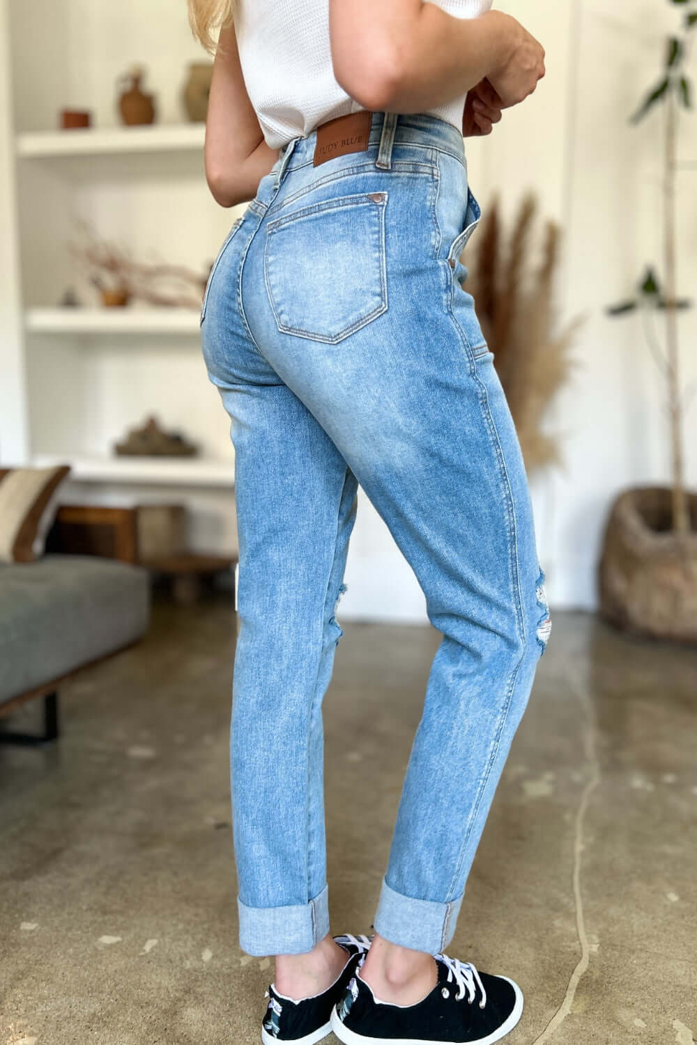 Woman wearing Judy Blue distressed straight jeans with patch pockets and high waist in a casual indoor setting