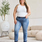 Woman modeling Judy Blue release hem cropped bootcut jeans in a modern living room setting.