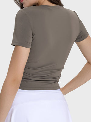 Back view of Millennia Ruched Round Neck Short Sleeve Active T-Shirt in mocha, showcasing its stylish and fitted design.