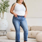 Woman wearing Judy Blue release hem cropped bootcut jeans in a modern living room.