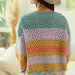 Back view of a woman in a colorful wavy hem openwork sweater and wide-brimmed hat, showcasing its trendy design.