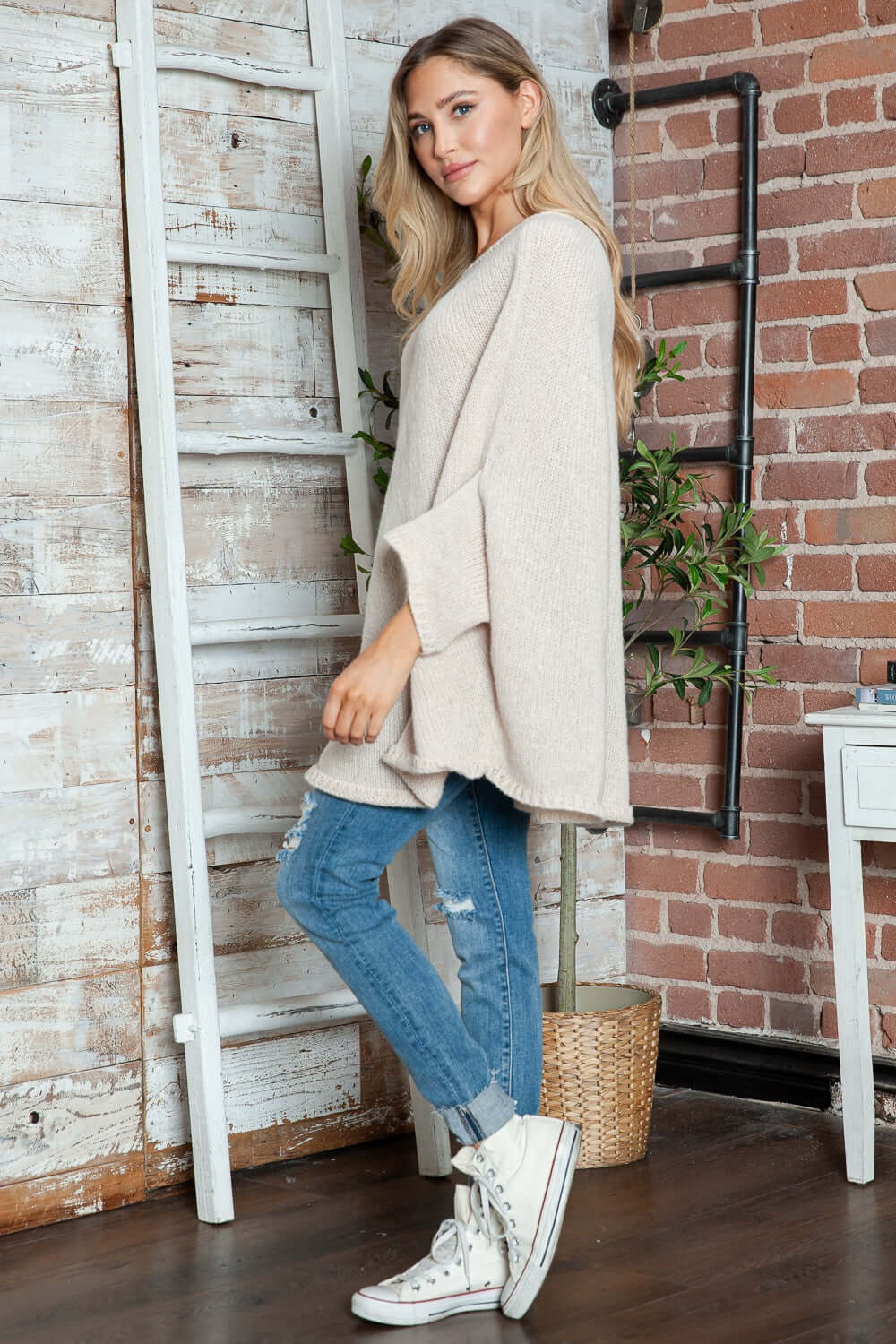 Cozy Bella Road Batwing Sleeve Sweater styled with jeans and sneakers in a chic room setting.