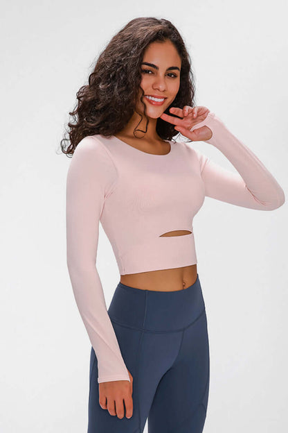 Woman wearing a pink long-sleeve cropped top with a cutout, perfect for stylish workouts.