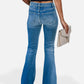 Back view of person wearing blue button fly bootcut jeans with pockets, holding a clutch bag, showcasing slightly stretchy denim fabric.