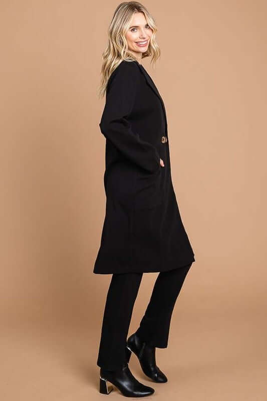 Stylish woman in a black double-breasted lapel collar coat with pockets, exuding elegance and confidence.