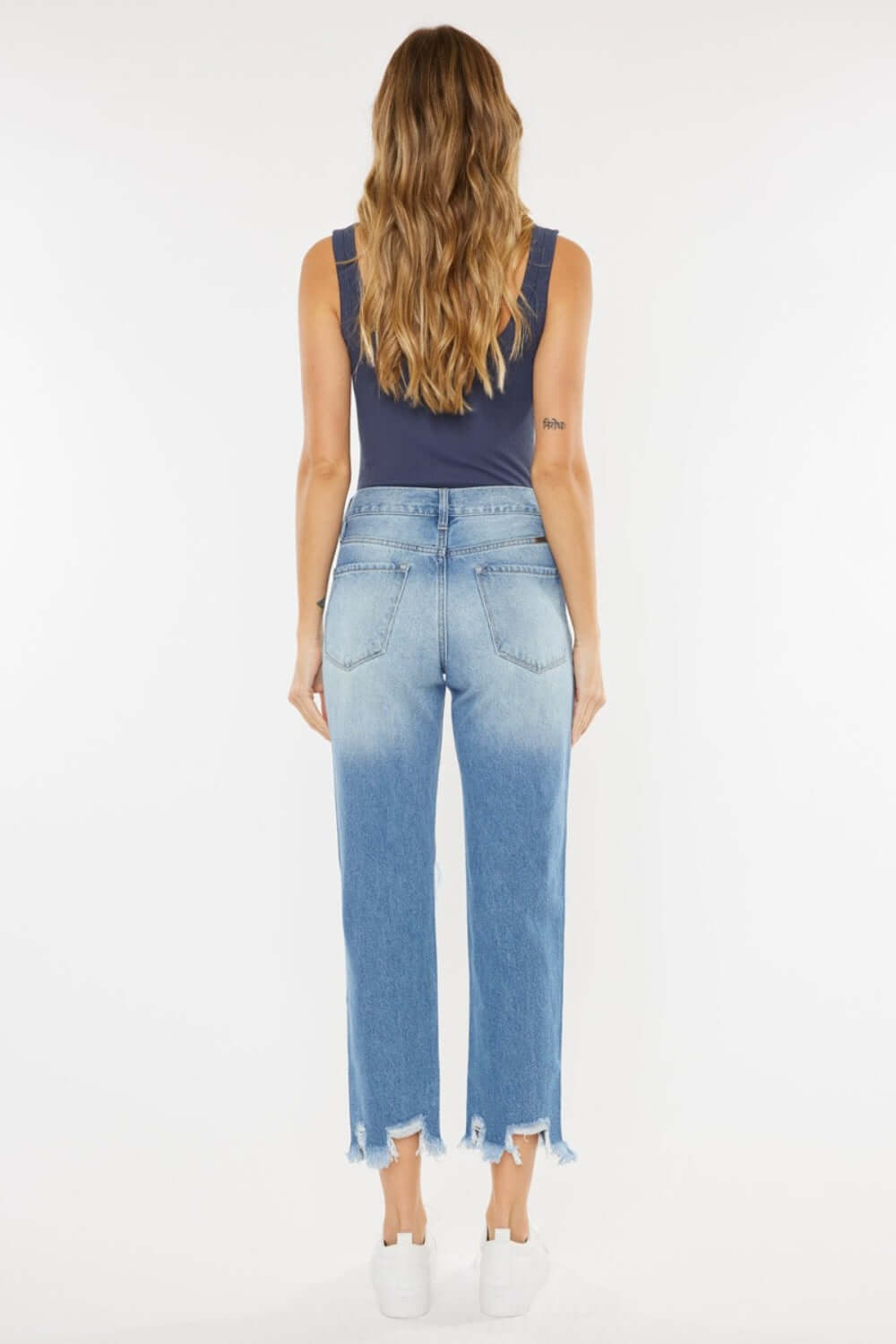 Back view of model wearing High Waist Chewed Up Straight Mom Jeans with distressed holes and frayed edges for a trendy, vintage-inspired look.