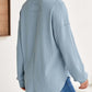 Woman wearing a light blue waffle-knit Johnny collar long sleeve sweatshirt, shown from the back with slightly stretchy material and a casual fit.