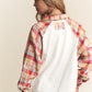 Woman wearing J.NNA plaid contrast button-down henley top with jeans, showcasing back view and colorful plaid sleeves.