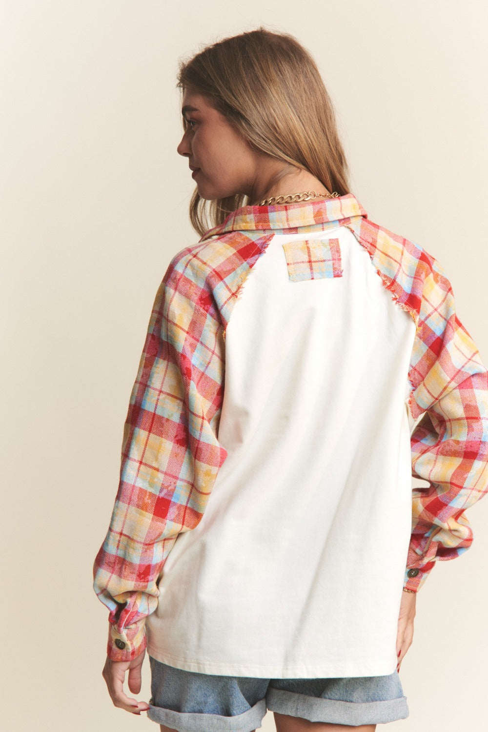 Woman wearing J.NNA plaid contrast button-down henley top with jeans, showcasing back view and colorful plaid sleeves.