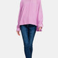 Woman wearing Zenana high-low side slit round neck t-shirt in pink paired with blue jeans, showcasing casual chic style.