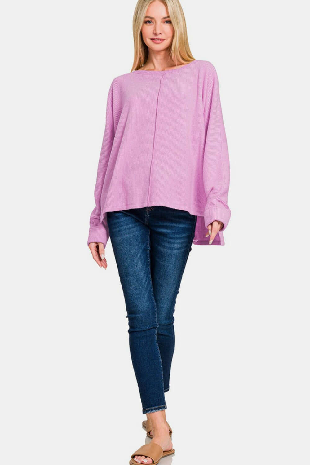 Woman wearing Zenana high-low side slit round neck t-shirt in pink paired with blue jeans, showcasing casual chic style.